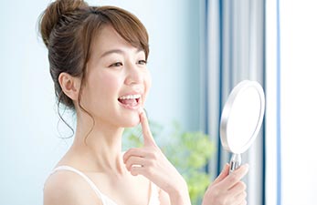 鏡を見て歯の白さに笑みを浮かべる女性